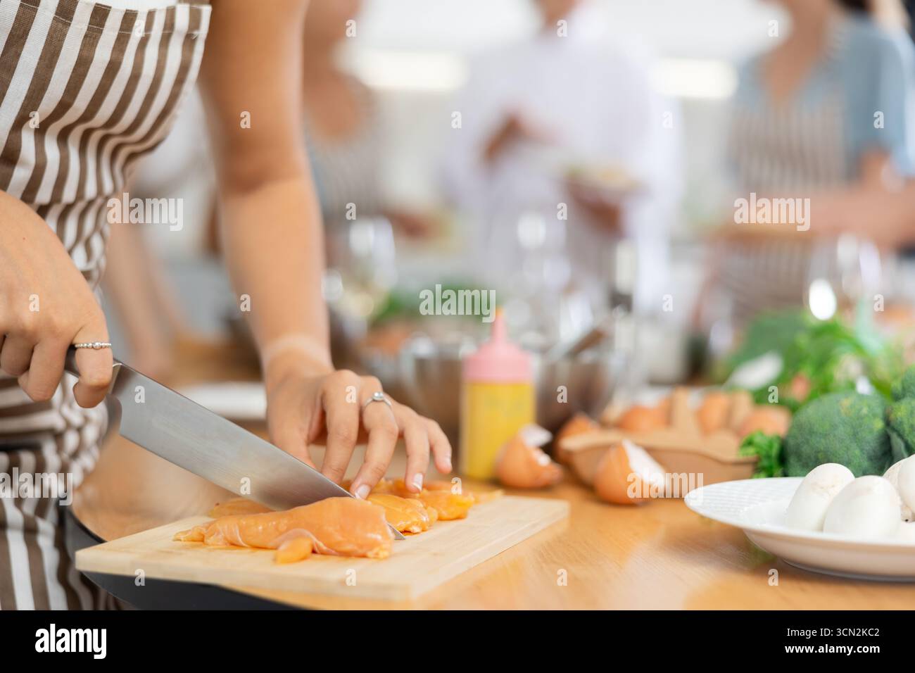 Frauen schneiden ein Stück Hähnchenfilet mit Händen und erledigen die Aufgabe im kulinarischen Meisterkurs. Nahaufnahme Stockfoto