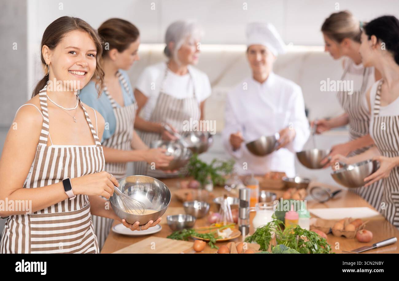 Mädchen während des Studiums in einem kulinarischen Workshop kocht sie appetitliche Soße, Marinade und Teig in einer Schüssel. Stockfoto