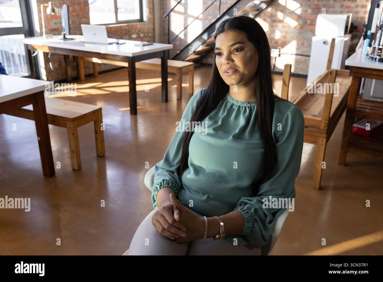 Frau, die im Büro in einem weißen Stuhl sitzt und einen Laptop mit Notebook benutzt, Kopierraum Stockfoto