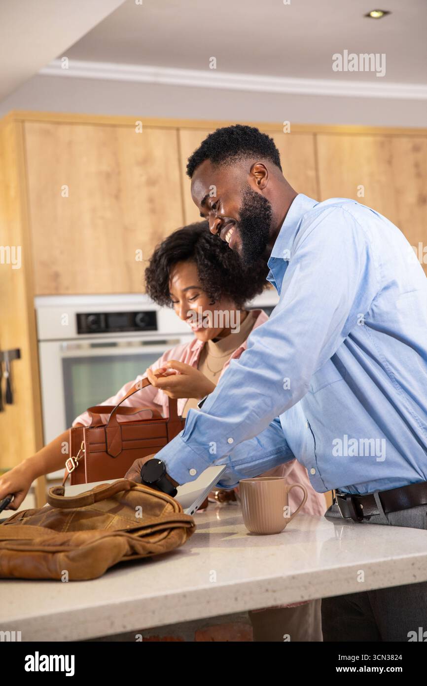 Diverse Paare lächeln und Gegenstände aus der Ledertasche holen, Handtasche auf der Kücheninsel mit Becher Stockfoto