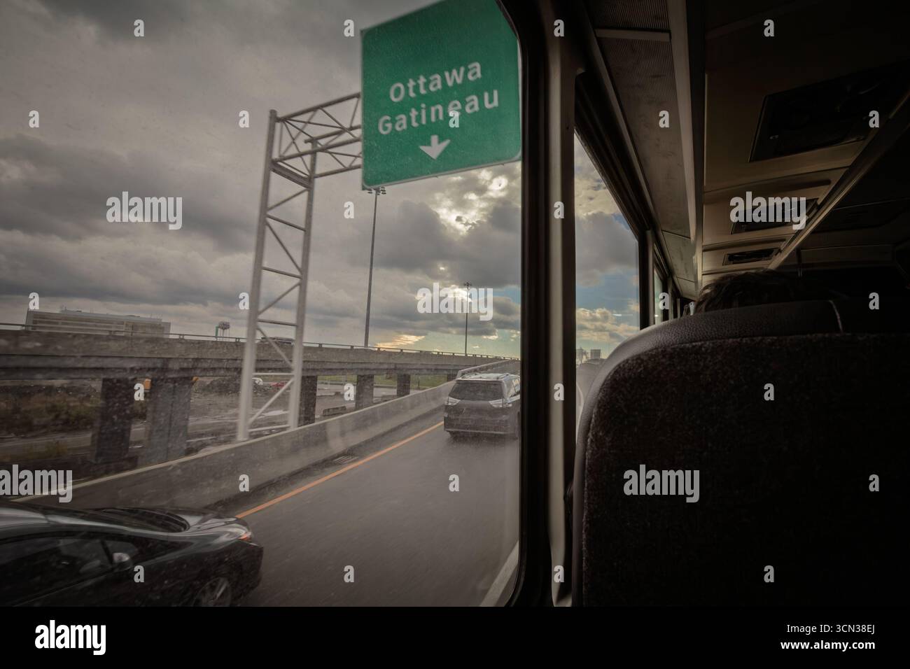 Straßenbild von einem Busfenster auf einer Quebec-Straße aus mit einem grünen Schild in Richtung Ottawa und Gatineau, Verkehrsstraßen, Überführungen und einem Clou Stockfoto