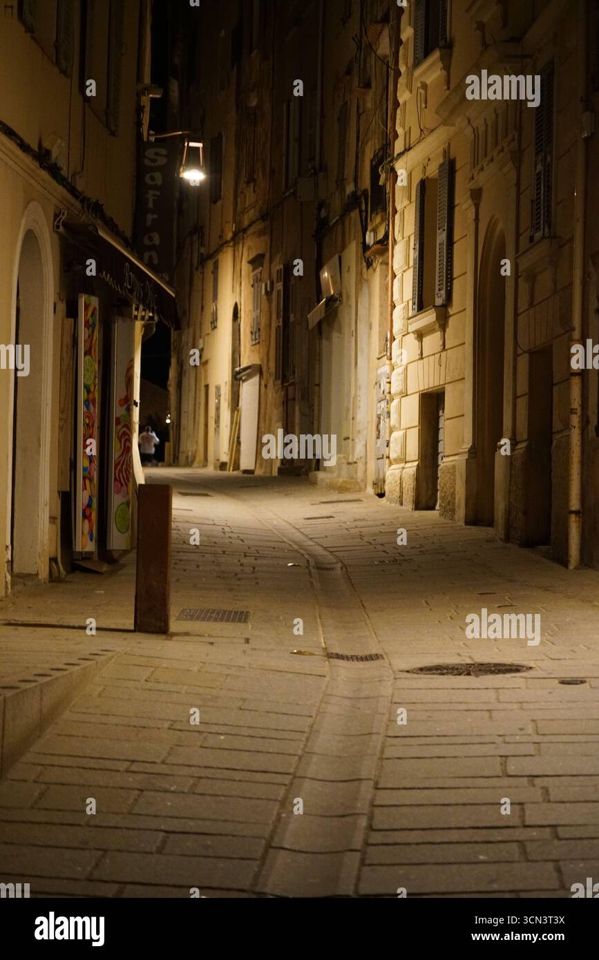 Ruhige Nachtallee Mit Warmen Straßenlichtern, Die Schmale Europäische Steinfassaden Beleuchten. Bonifacio, Korsika, Frankreich Stockfoto