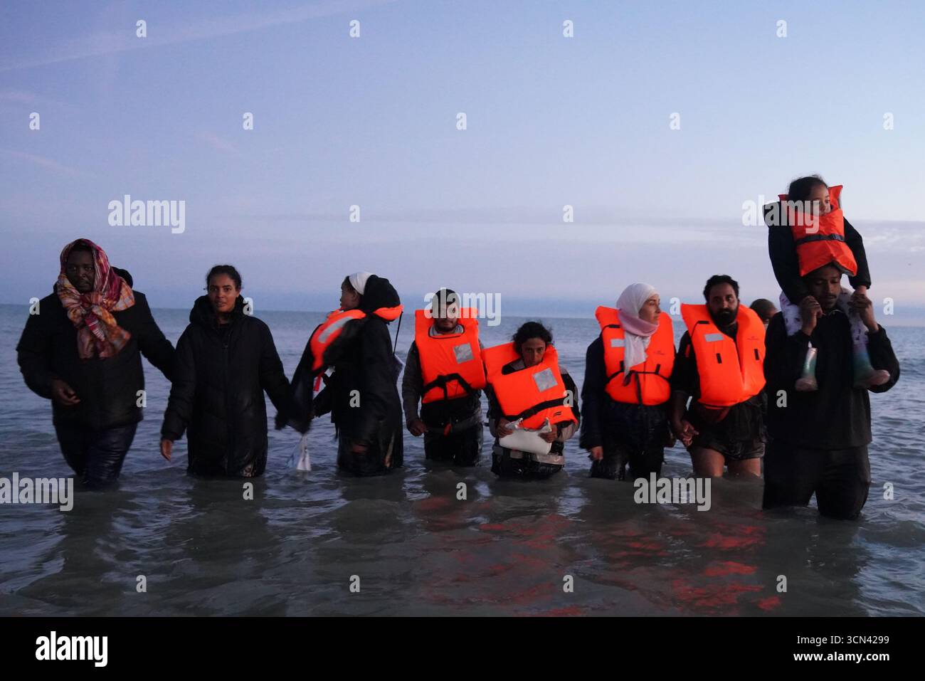 Eine Gruppe von Menschen, die als Migranten gelten, waten in der Nähe von Gravelines in Frankreich ins Meer. Bilddatum: Freitag, 19. September 2025. Stockfoto