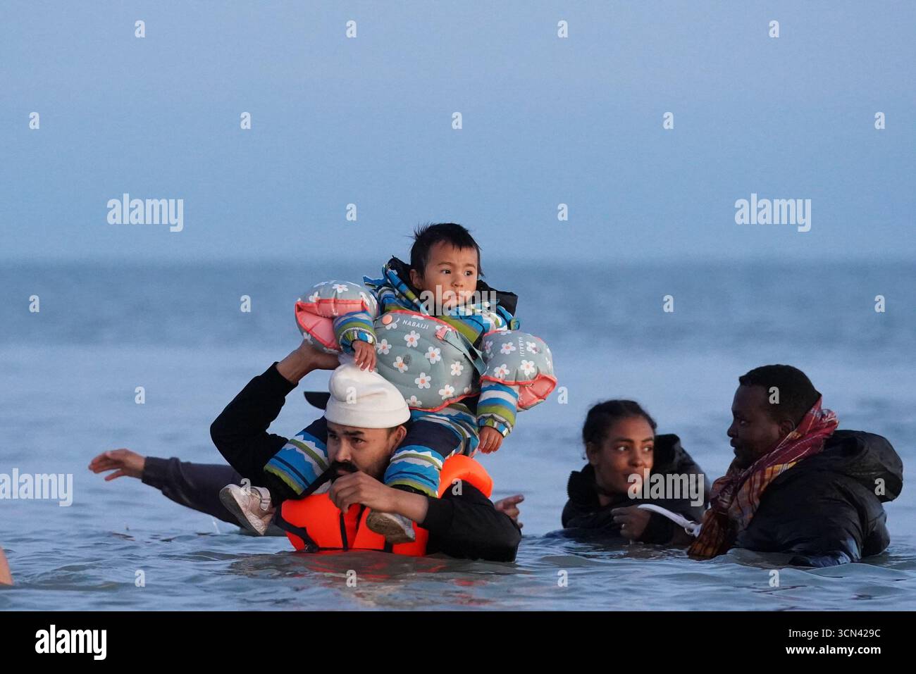 Eine Gruppe von Menschen, die als Migranten gelten, waten in der Nähe von Gravelines in Frankreich ins Meer. Bilddatum: Freitag, 19. September 2025. Stockfoto