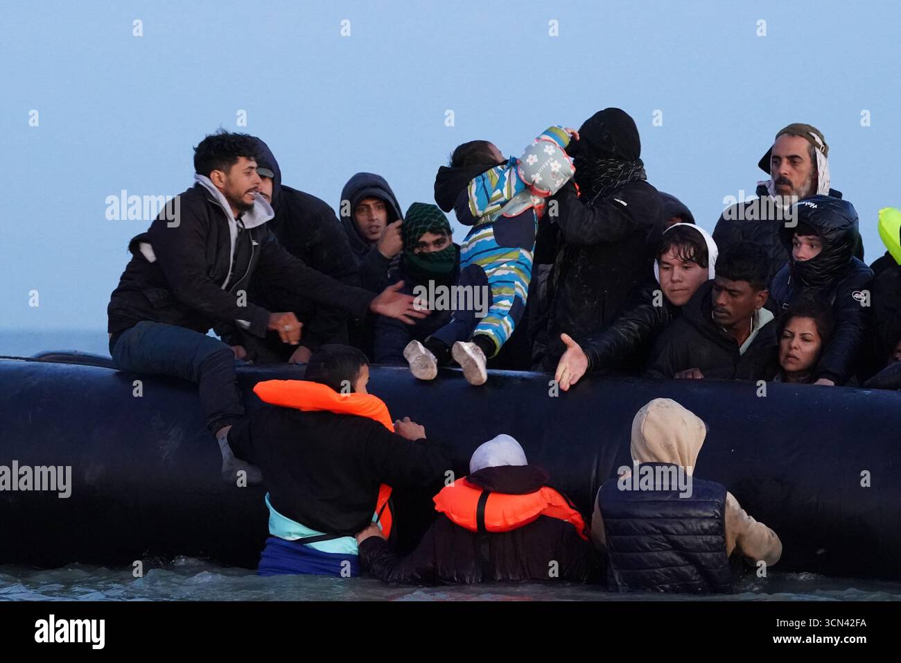 Eine Gruppe von Menschen, die als Migranten gelten, waten in der Nähe von Gravelines in Frankreich ins Meer, um sich einem Boot anzuschließen. Bilddatum: Freitag, 19. September 2025. Stockfoto
