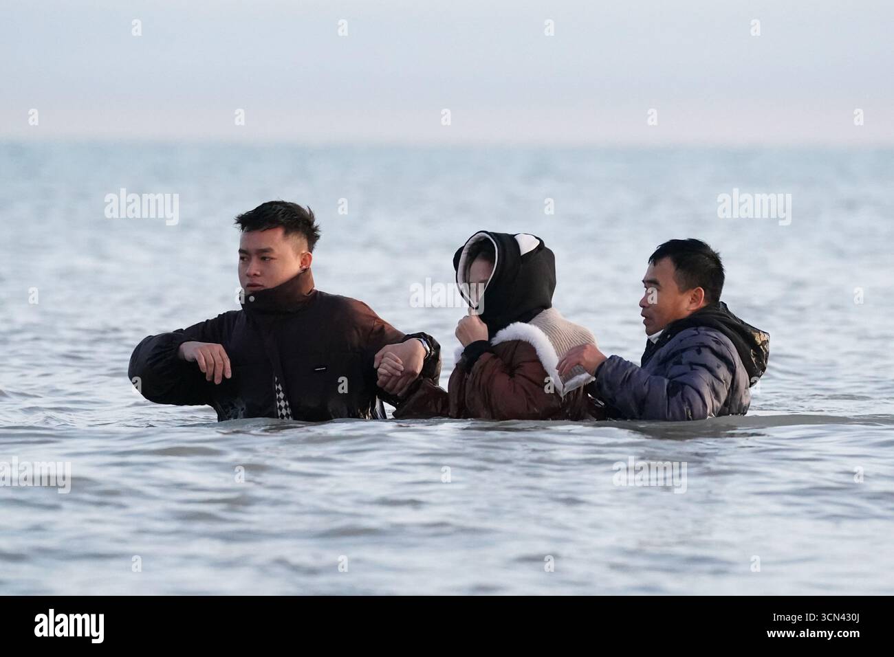Eine Gruppe von Menschen, die als Migranten gelten, waten in der Nähe von Gravelines in Frankreich ins Meer. Bilddatum: Freitag, 19. September 2025. Stockfoto