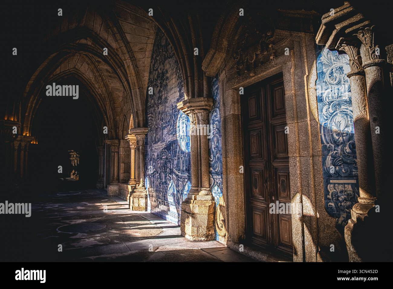Sonnendurchfluteter Durchgang mit Azulejo-Fliesen und Steinsäulen im Kloster der Kathedrale von Porto, Portugal Stockfoto