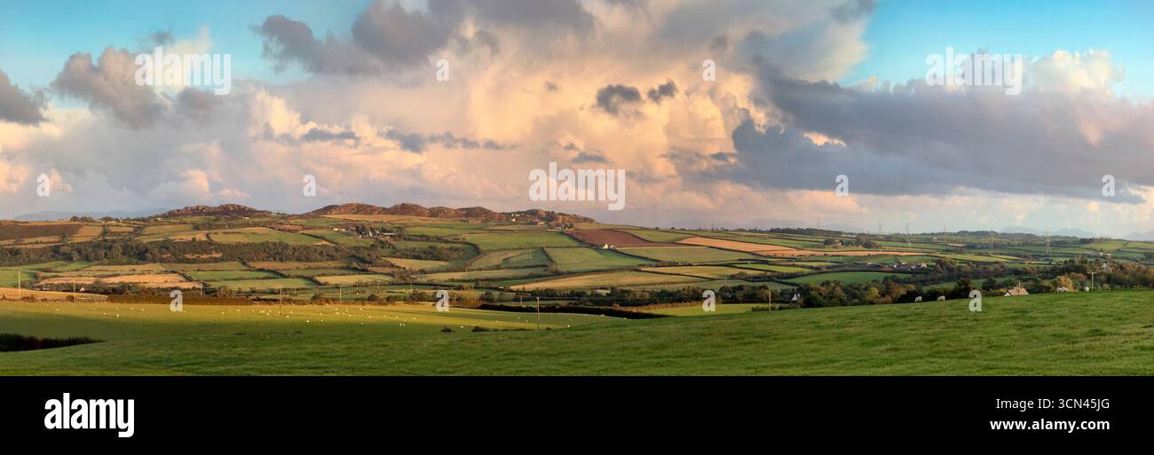 Panoramablick auf die Sonne am späten Nachmittag auf Donnern Wolken über einer ländlichen Landschaft der Landschaft von Anglesey in Nordwales, Großbritannien. Stockfoto