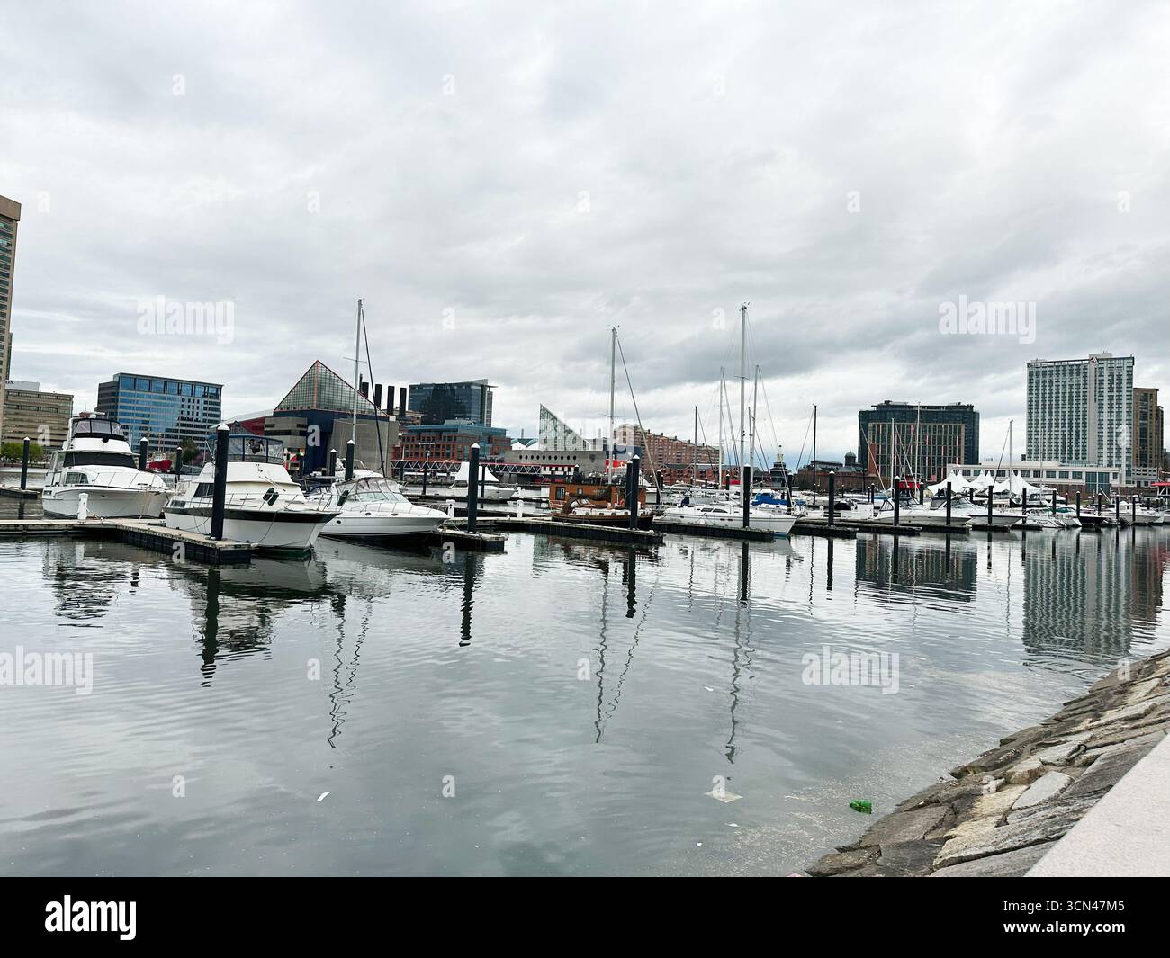 Baltimore, Maryland, USA - 10. April 2025: Boote legten an einem modernen Yachthafen an, mit einem urbanen Stadtbild von Baltimore, USA. Stockfoto
