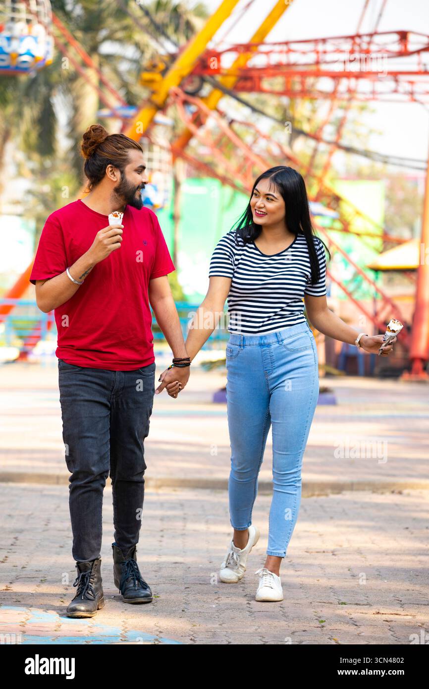 Ein Paar hält Hände und genießt Eis im Vergnügungspark - Fun Date Moment Stockfoto