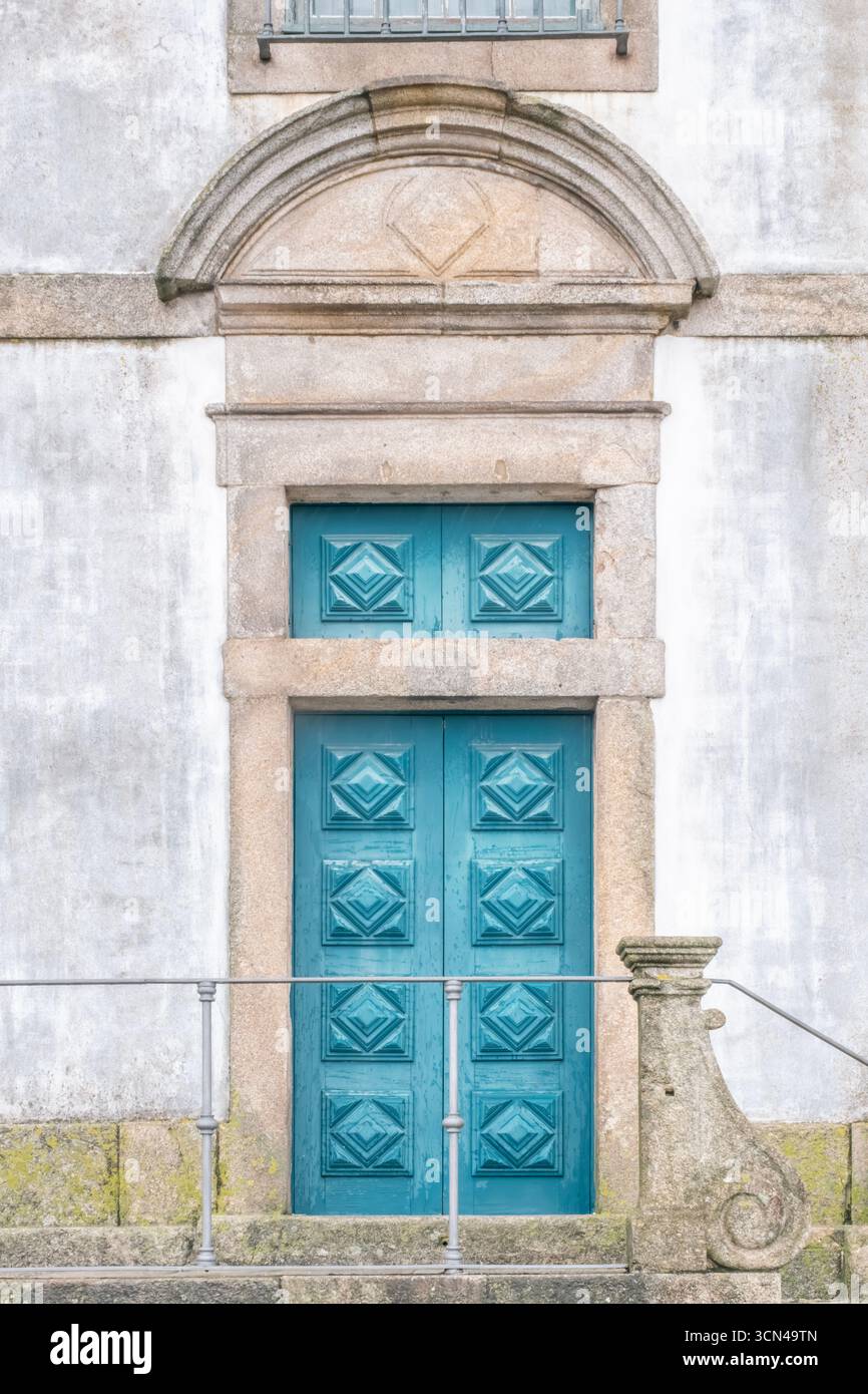 Blaue Holztür Mit Diamantpaneelen Im Historischen Porto Portugal, Eingerahmt Von Steinbogen Und Balkon. Dekorative Fassade, Altstadtarchitektur, Kulturerbe Stockfoto