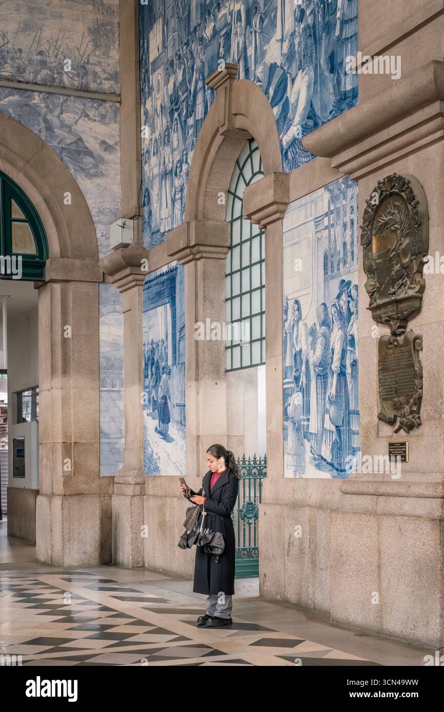 Frau Mit Telefon Im Berühmten Sao Bento Bahnhof Porto Portugal. Historische Azulejo-Fliesen, portugiesisches Wahrzeichen, Reisefotografie Stockfoto