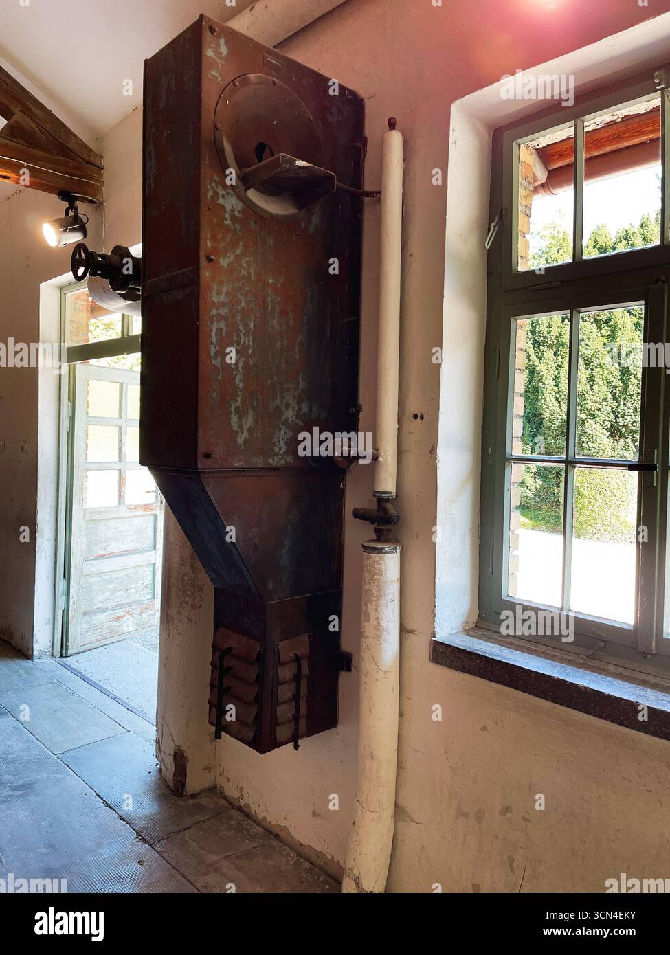 Dachau, Deutschland - 29. September 2022: Rostende Industriemaschine in der Nähe eines Fensters im KZ Dachau. Stockfoto