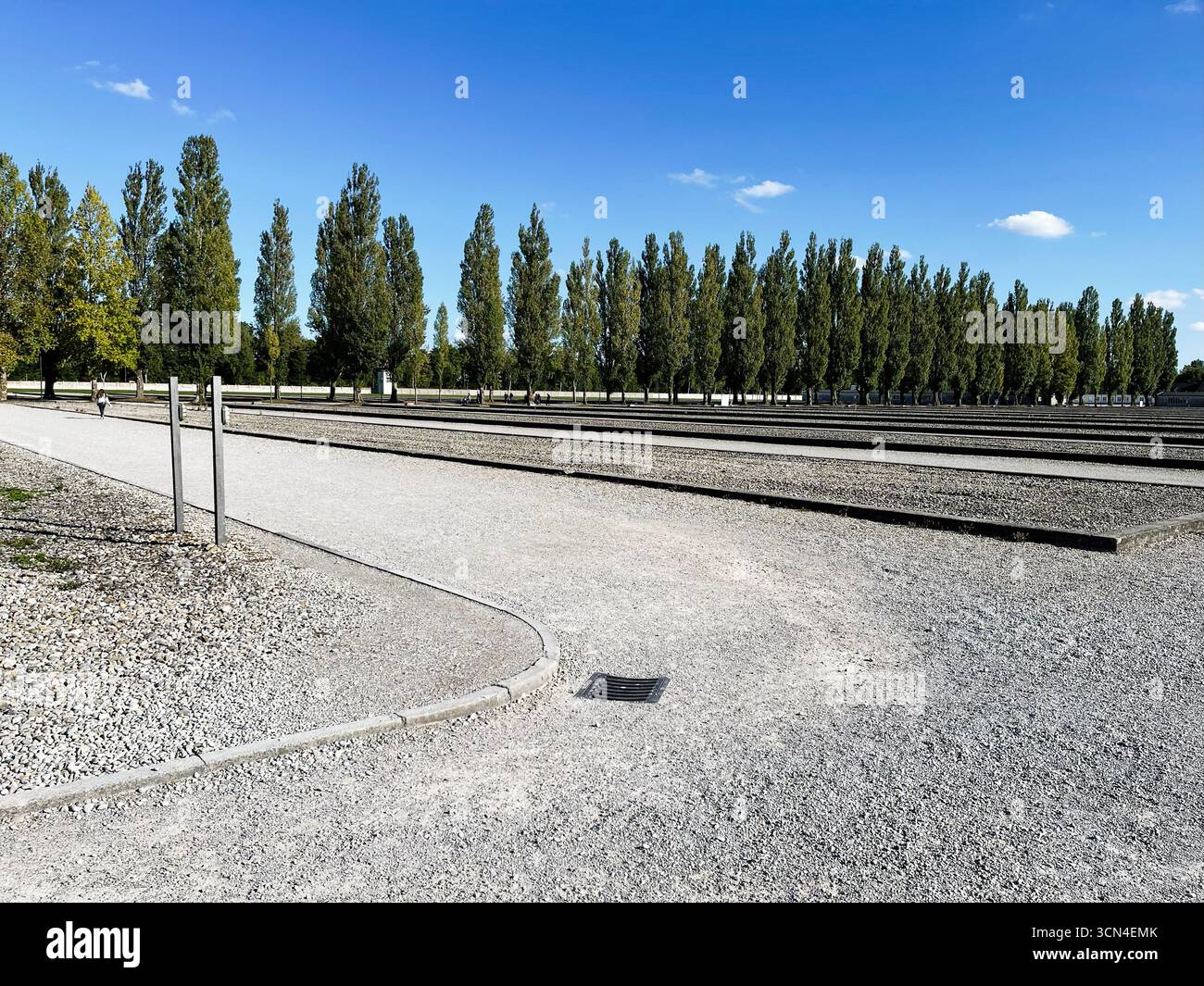 Dachau, Deutschland - 29. September 2022: Wege im Konzentrationslager Dachau, umgeben von Bäumen an einem sonnigen Tag Stockfoto