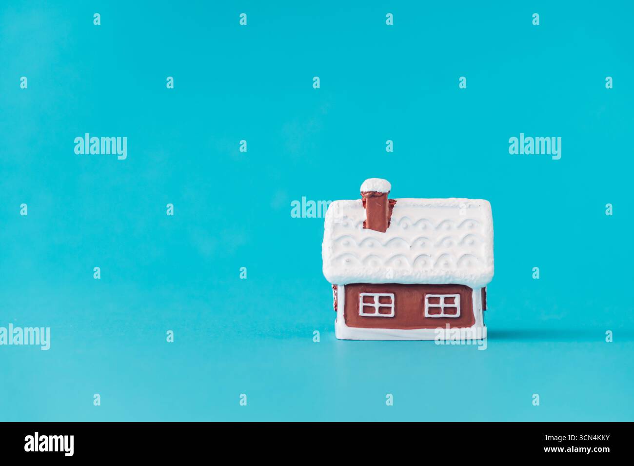 Winterhaus auf blauem Hintergrund. Minimales Konzept und Einfachheit. Weihnachts- und Neujahrsidee. Stockfoto