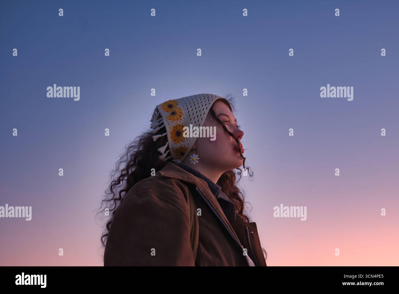 Frau, die in die Ferne schaut mit rosa Sonnenuntergang-Himmel-Hintergrund Stockfoto