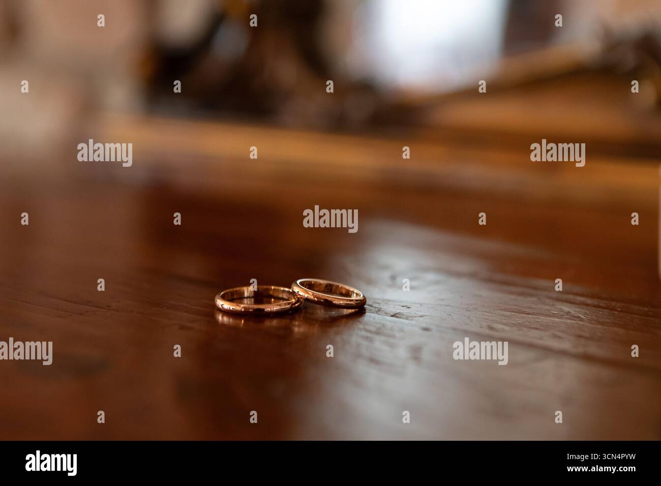 Zwei goldene Eheringe auf Holztisch: Symbol für ewige Liebe und Hingabe Stockfoto