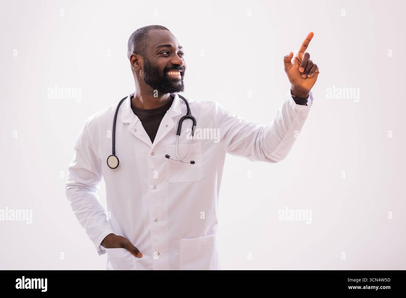 Porträt eines männlichen Afroamerikaners, der eine Idee hat und auf dem grauen Hintergrund nach oben zeigt. Stockfoto