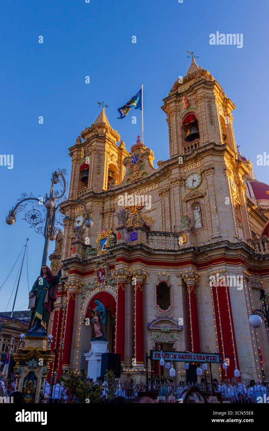 Zabbar, Malta - 14. September 2025 Nachtblick auf die beleuchtete barocke Kirchenfassade mit Festivaldekor Stockfoto