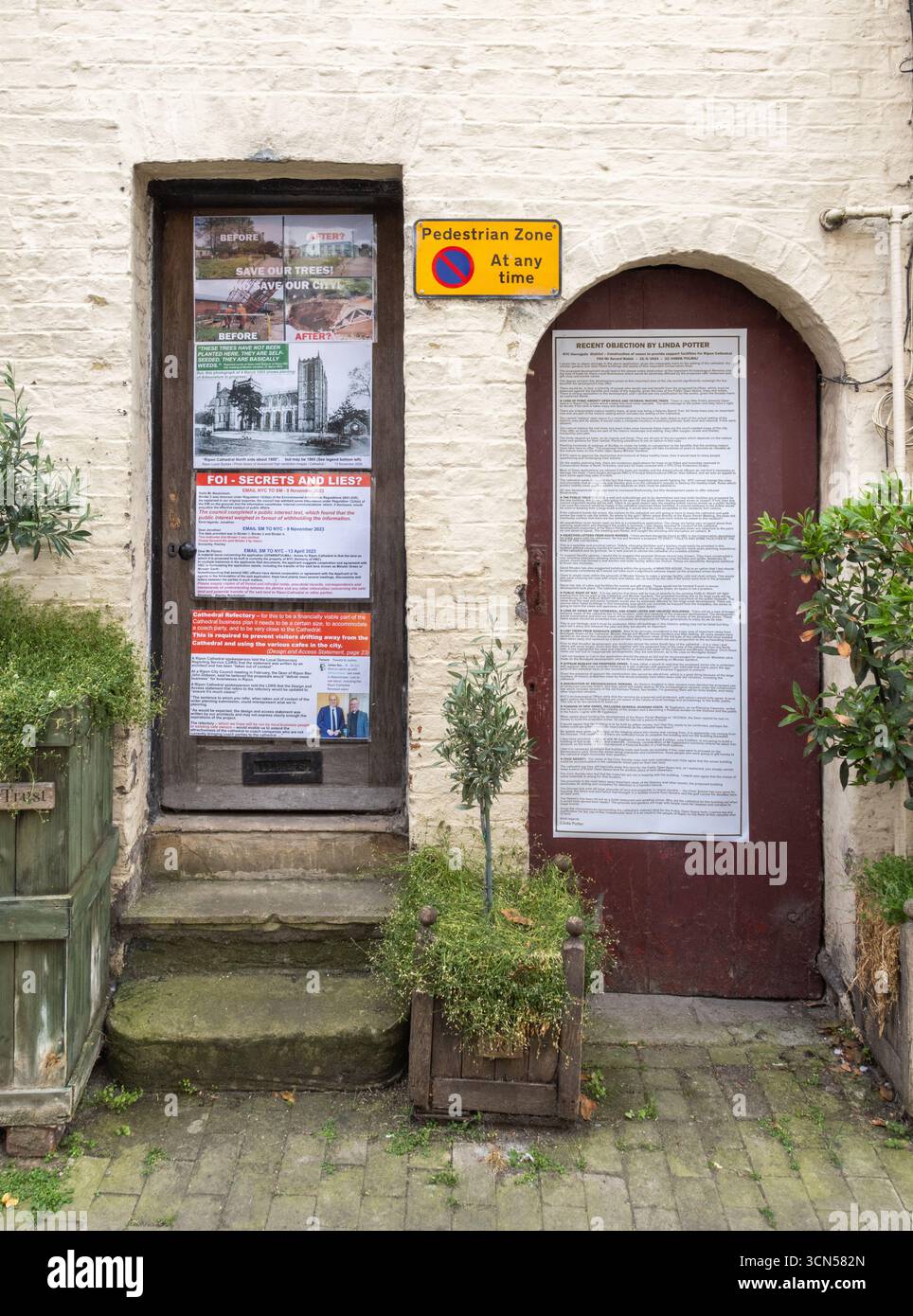 Protestplakate und Anschlagtafeln in Ripon, North Yorkshire, die sich gegen die Pläne der Kathedrale von Ripon widersetzen und an Türen entlang einer Fußgängerzone angebracht sind Stockfoto