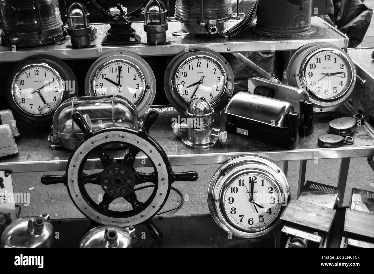 PARIS, FRANKREICH - 13. JANUAR 2013: Alte Uhren und Bootslenkrad zum Verkauf auf dem Flohmarkt Boulevard de l'Hopital. Schwarzweißes historisches Foto. Stockfoto