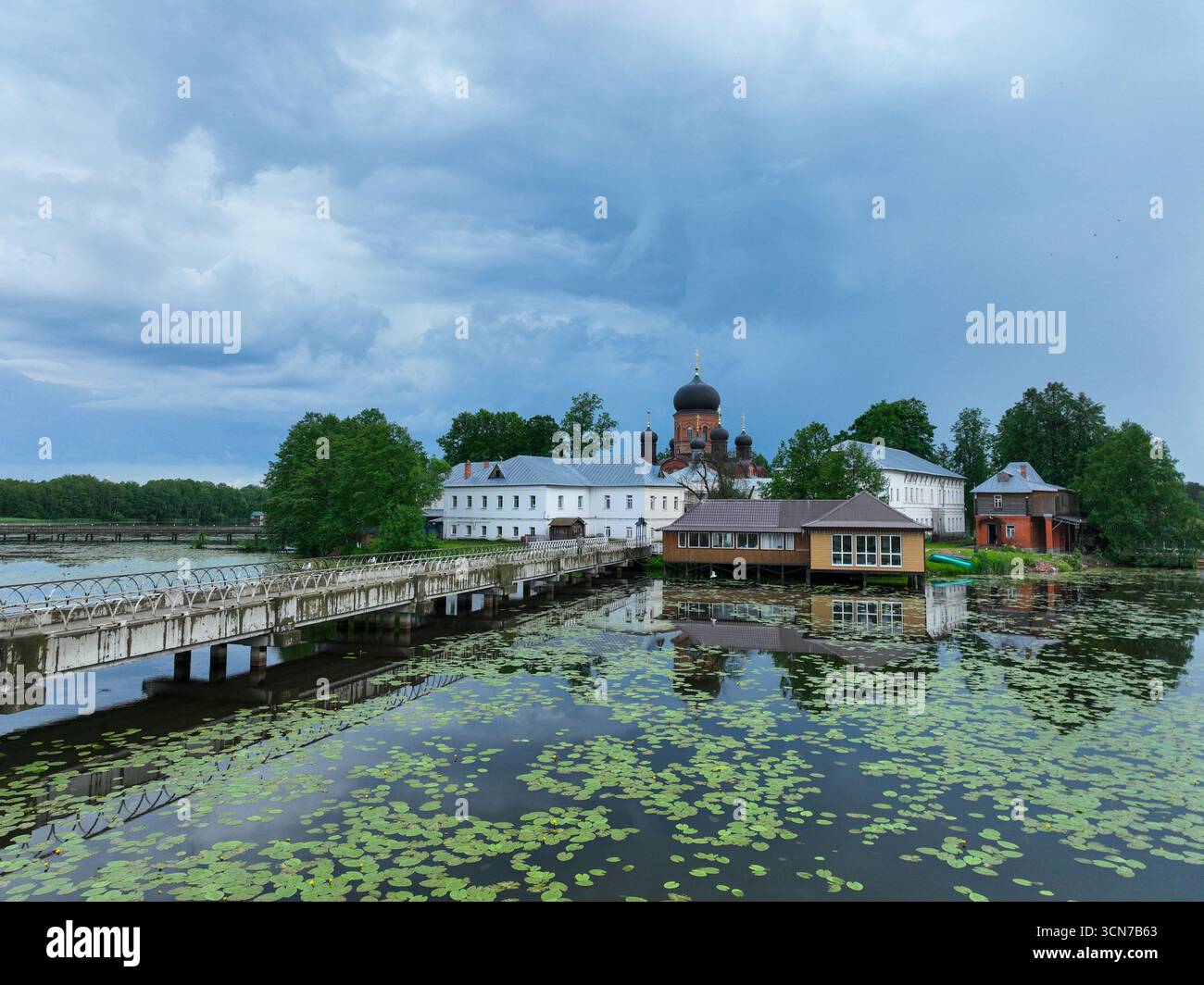 Ein flacher Blick aus der Vogelperspektive auf das Kloster der Insel Vvedenski, das die Gebäude und Fußgängerbrücken zeigt, die die Insel mit der üppigen grünen Küste verbinden. Stockfoto
