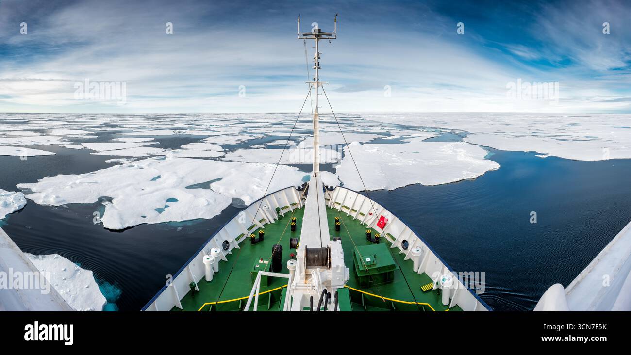 Eisverstärktes Expeditionsschiff, das sich durch Meereis nördlich von Svalbard schiebt | SJUØYANE (SIEBEN INSELN), Svalbard — Ein eisverstärktes Expeditionsschiff teilt ein Feld aus Meereis nördlich von Svalbard, sein verstärkter Bug schneidet durch Eisschollen unter einem weiten arktischen Himmel. Diese Gewässer behinderten Constantine Phipps' HMS Racehorse und HMS Carcass im Jahr 1773, und William Parry startete seinen Schlittenboot-Versuch für den Nordpol 1827 von der nahe gelegenen Waldenøya aus und erreichte einen Rekordpunkt von 82°45′N im Norden. Stockfoto