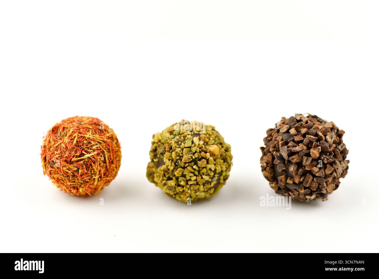 Drei verschiedenfarbige Kugeln, von denen eine braun ist. Die anderen beiden sind grün und orange. Die Bälle sitzen auf weißem Hintergrund Stockfoto