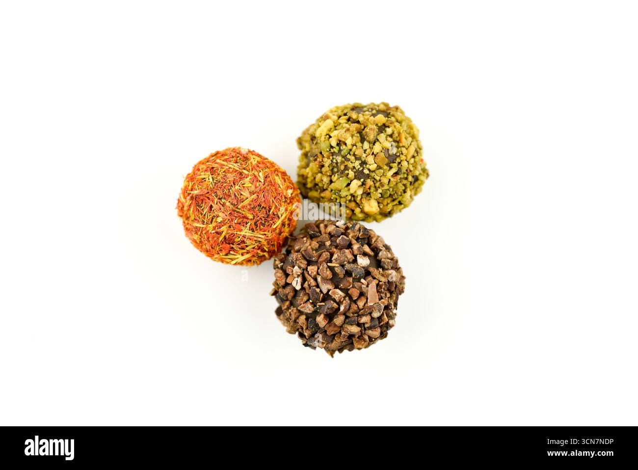 Drei Schokoladenkugeln mit Nüssen darauf. Die Nüsse sind braun und die Kugeln rund. Das Konzept von Genuss und Luxus Stockfoto