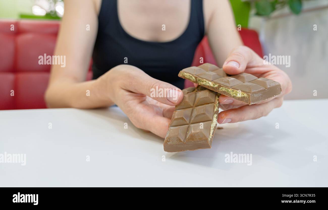 Nahaufnahme einer Person, die einen hochwertigen Milchschokoladenriegel zart aufteilt und das faszinierende Pistazien-ähnliche Interieur, Gourmet-Vergnügen fr Stockfoto