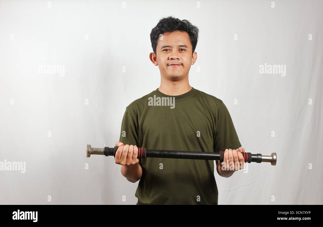 Asiatischer Mann mit grünem T-Shirt, der Krafttraining mit leichten Kurzhanteln macht Stockfoto