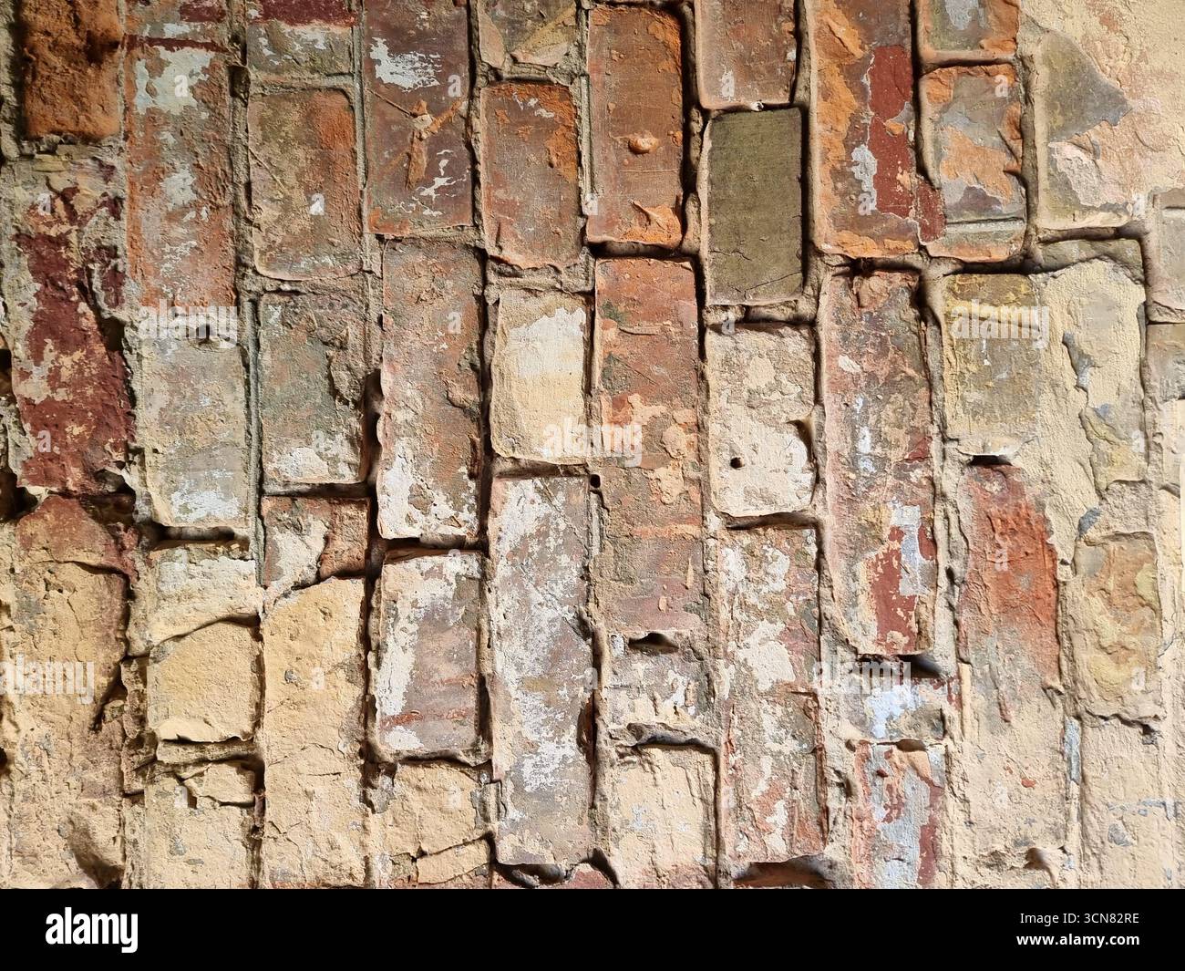 Alte Ziegelwand aus roten und gelben Kiewer Ziegeln im Hochformat. Starke Kontrastbeleuchtung hebt die veraltete Textur hervor und erzeugt ein Au Stockfoto