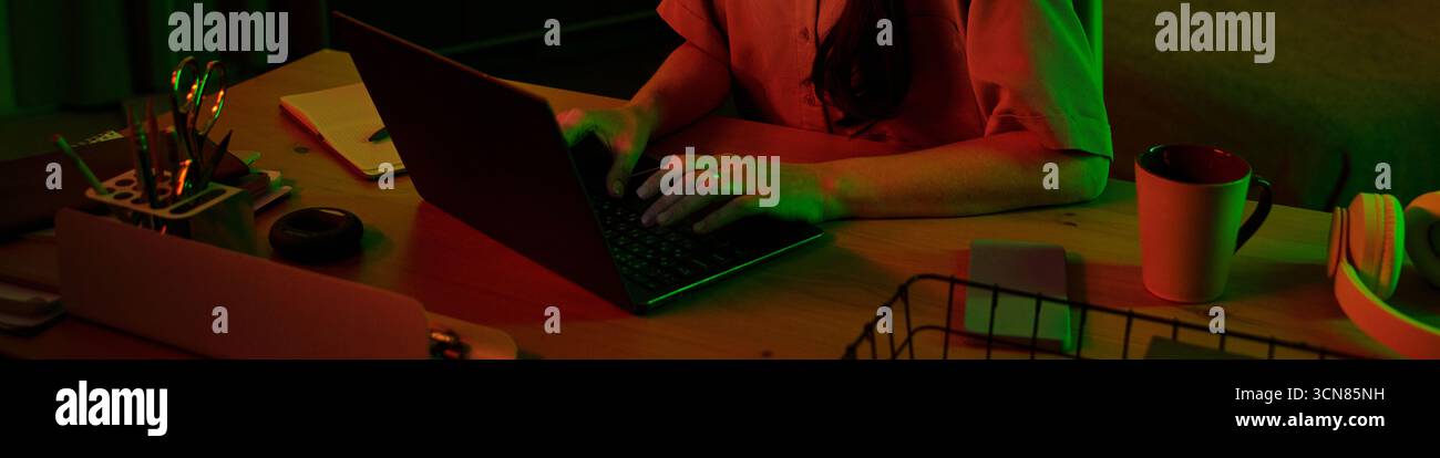 Frau tippt auf dem Laptop, während sie spät nachts arbeitet Stockfoto