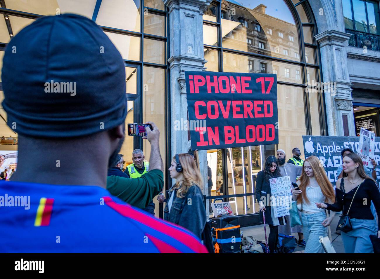 Aktivisten veranstalteten am 17. September einen Protest vor dem Apple Store in der Regent Street, Central London, während des Launch des iPhone 17. Demonstranten hielten Plakate, auf denen sie erklärten, dass das iPhone 17 mit Blut bedeckt ist, und beschuldigten Apple, vom Kobaltbergbau im Kongo im Zusammenhang mit Kinderarbeit und Menschenrechtsverletzungen profitiert zu haben. Die Warteschlangen von Kunden, die versuchten, den Regent Street Apple Store zu betreten, wurden mit Gesängen, Plakaten und Zuschauern getroffen, die sich versammelten, um den Protest zu beobachten. Stockfoto