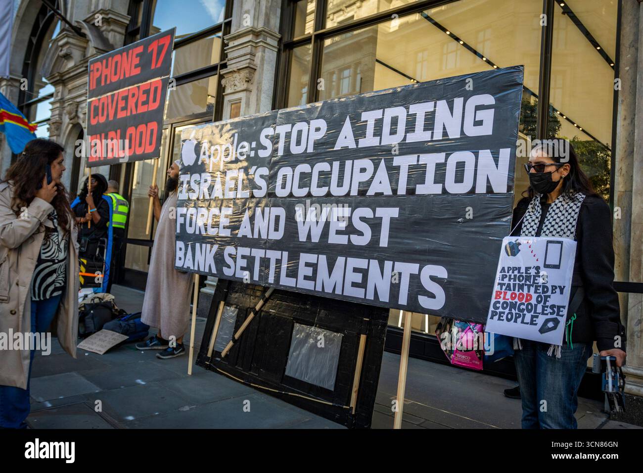 Aktivisten veranstalteten am 17. September einen Protest vor dem Apple Store in der Regent Street, Central London, während des Launch des iPhone 17. Demonstranten hielten Plakate, auf denen sie erklärten, dass das iPhone 17 mit Blut bedeckt ist, und beschuldigten Apple, vom Kobaltbergbau im Kongo im Zusammenhang mit Kinderarbeit und Menschenrechtsverletzungen profitiert zu haben. Die Warteschlangen von Kunden, die versuchten, den Regent Street Apple Store zu betreten, wurden mit Gesängen, Plakaten und Zuschauern getroffen, die sich versammelten, um den Protest zu beobachten. Stockfoto