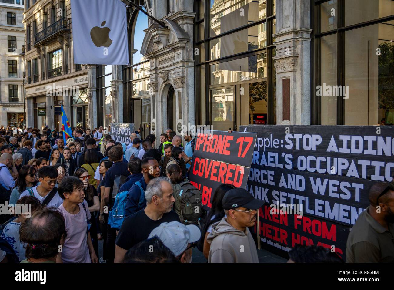 Aktivisten veranstalteten am 17. September einen Protest vor dem Apple Store in der Regent Street, Central London, während des Launch des iPhone 17. Demonstranten hielten Plakate, auf denen sie erklärten, dass das iPhone 17 mit Blut bedeckt ist, und beschuldigten Apple, vom Kobaltbergbau im Kongo im Zusammenhang mit Kinderarbeit und Menschenrechtsverletzungen profitiert zu haben. Die Warteschlangen von Kunden, die versuchten, den Regent Street Apple Store zu betreten, wurden mit Gesängen, Plakaten und Zuschauern getroffen, die sich versammelten, um den Protest zu beobachten. Stockfoto
