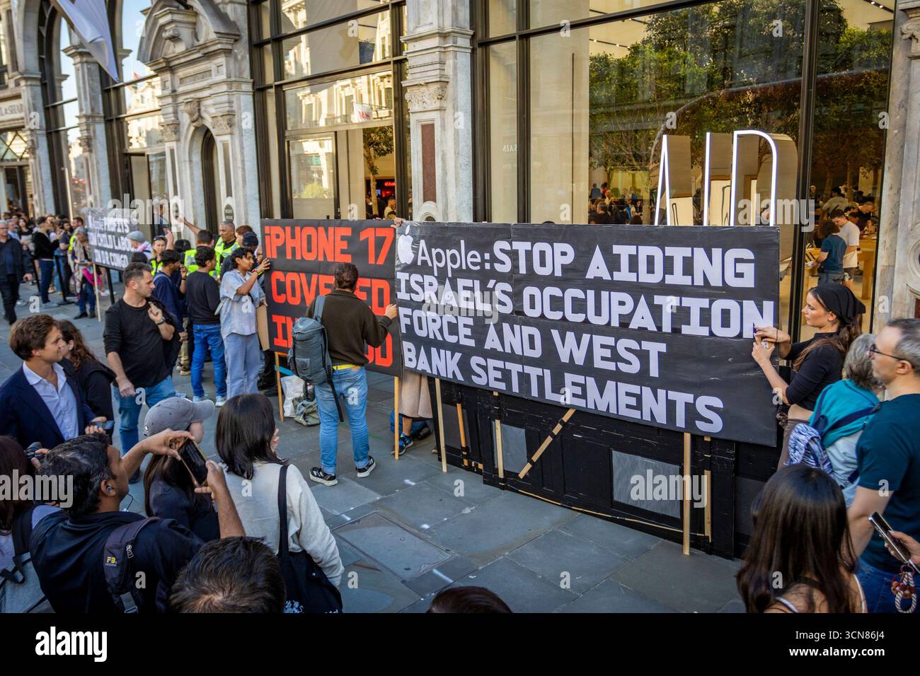 Aktivisten veranstalteten am 17. September einen Protest vor dem Apple Store in der Regent Street, Central London, während des Launch des iPhone 17. Demonstranten hielten Plakate, auf denen sie erklärten, dass das iPhone 17 mit Blut bedeckt ist, und beschuldigten Apple, vom Kobaltbergbau im Kongo im Zusammenhang mit Kinderarbeit und Menschenrechtsverletzungen profitiert zu haben. Die Warteschlangen von Kunden, die versuchten, den Regent Street Apple Store zu betreten, wurden mit Gesängen, Plakaten und Zuschauern getroffen, die sich versammelten, um den Protest zu beobachten. Stockfoto