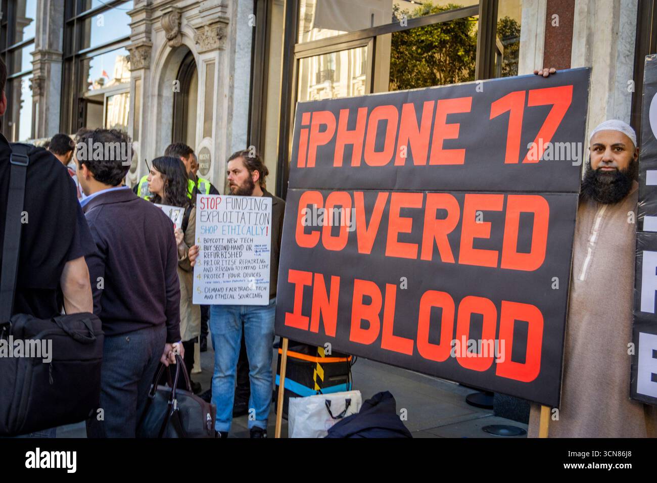 Aktivisten veranstalteten am 17. September einen Protest vor dem Apple Store in der Regent Street, Central London, während des Launch des iPhone 17. Demonstranten hielten Plakate, auf denen sie erklärten, dass das iPhone 17 mit Blut bedeckt ist, und beschuldigten Apple, vom Kobaltbergbau im Kongo im Zusammenhang mit Kinderarbeit und Menschenrechtsverletzungen profitiert zu haben. Die Warteschlangen von Kunden, die versuchten, den Regent Street Apple Store zu betreten, wurden mit Gesängen, Plakaten und Zuschauern getroffen, die sich versammelten, um den Protest zu beobachten. Stockfoto