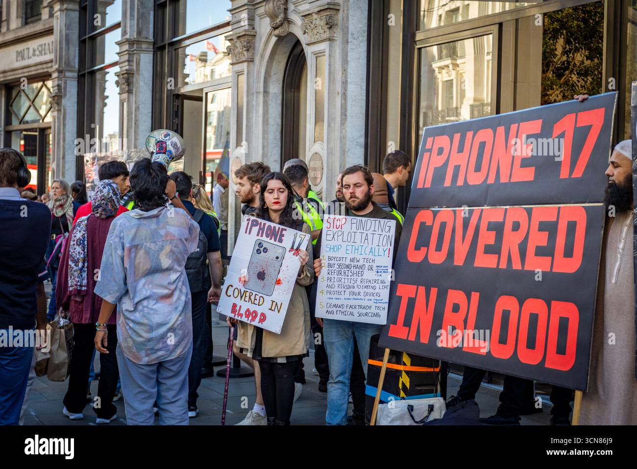 Aktivisten veranstalteten am 17. September einen Protest vor dem Apple Store in der Regent Street, Central London, während des Launch des iPhone 17. Demonstranten hielten Plakate, auf denen sie erklärten, dass das iPhone 17 mit Blut bedeckt ist, und beschuldigten Apple, vom Kobaltbergbau im Kongo im Zusammenhang mit Kinderarbeit und Menschenrechtsverletzungen profitiert zu haben. Die Warteschlangen von Kunden, die versuchten, den Regent Street Apple Store zu betreten, wurden mit Gesängen, Plakaten und Zuschauern getroffen, die sich versammelten, um den Protest zu beobachten. Stockfoto