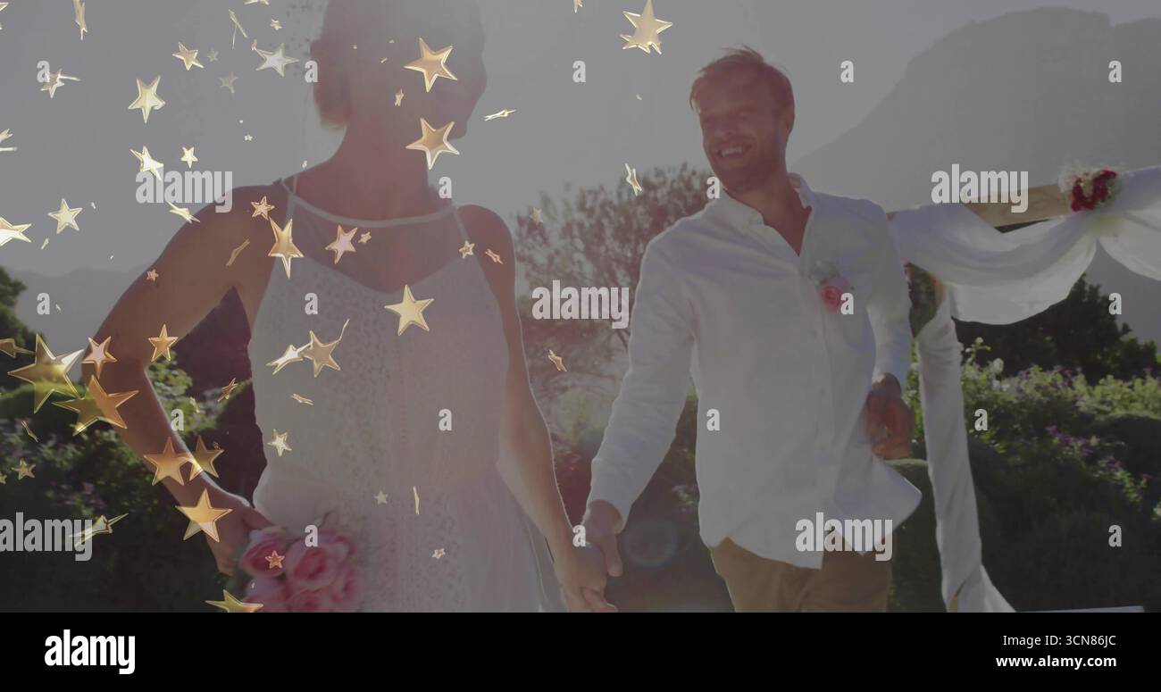 Ein wandelndes Paar in Hochzeitskleidung, das bei der Hochzeit die Hände hält, mit Bogen, rosa Blumenstrauß, goldenen Glitzern Stockfoto