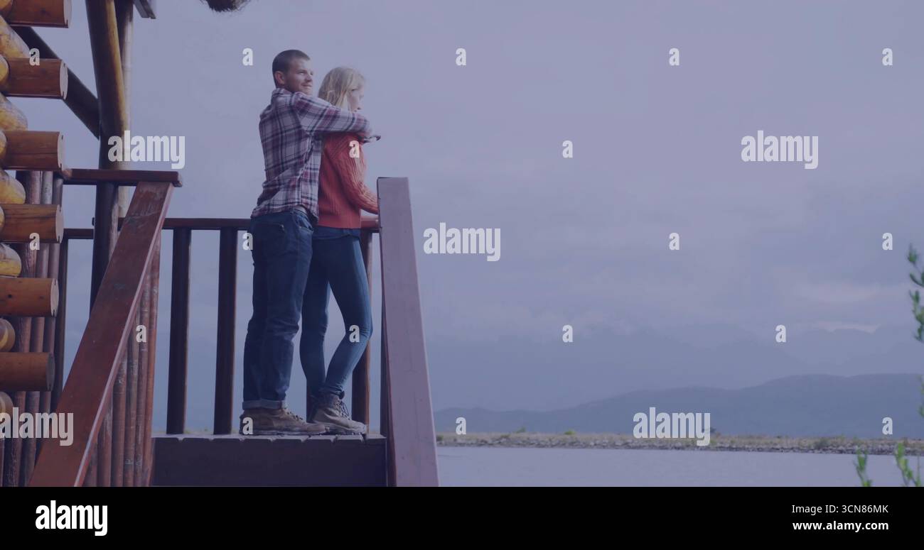 Stehendes Paar in Flanell, orangefarbener Strick mit Blick auf See und Berge am Kabinengeländer, Kopierraum Stockfoto