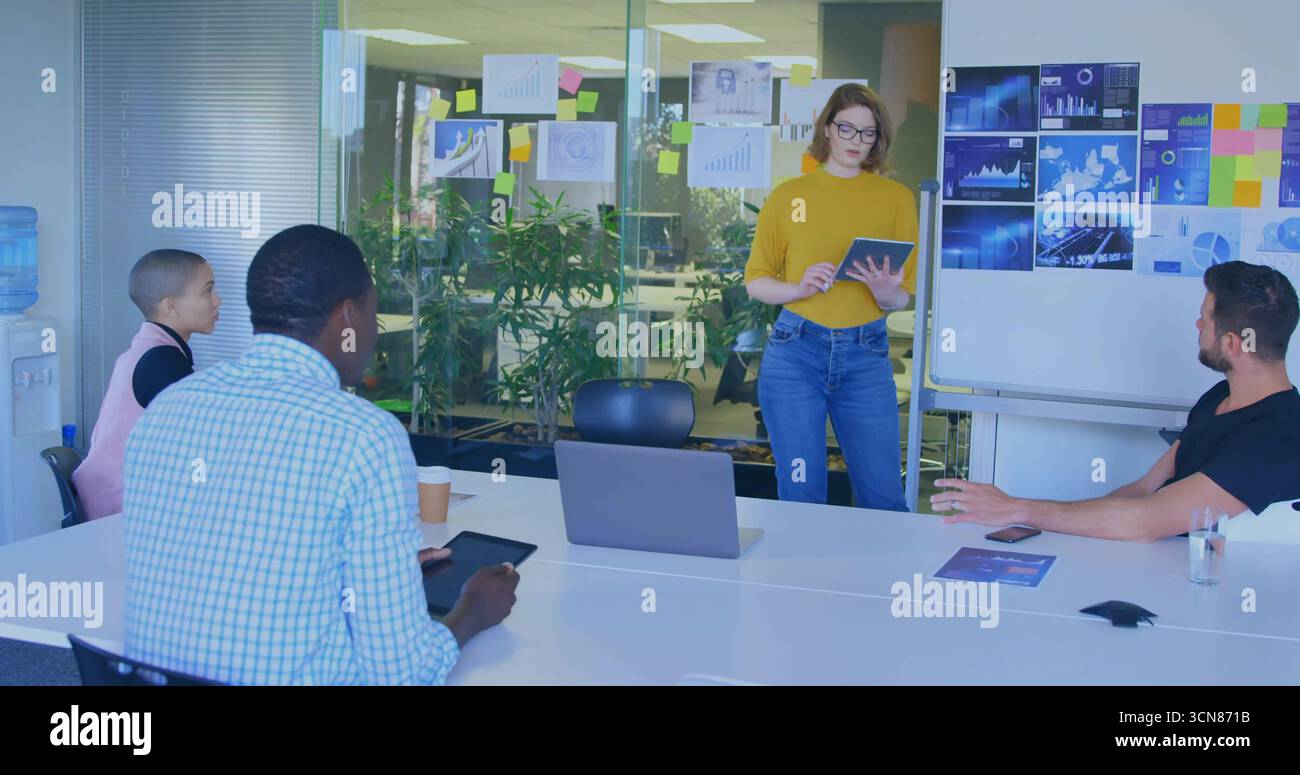 Führender Moderator mit Senfpullover, der Karten im Konferenzraum erklärt, mit Laptop-Tablet Stockfoto