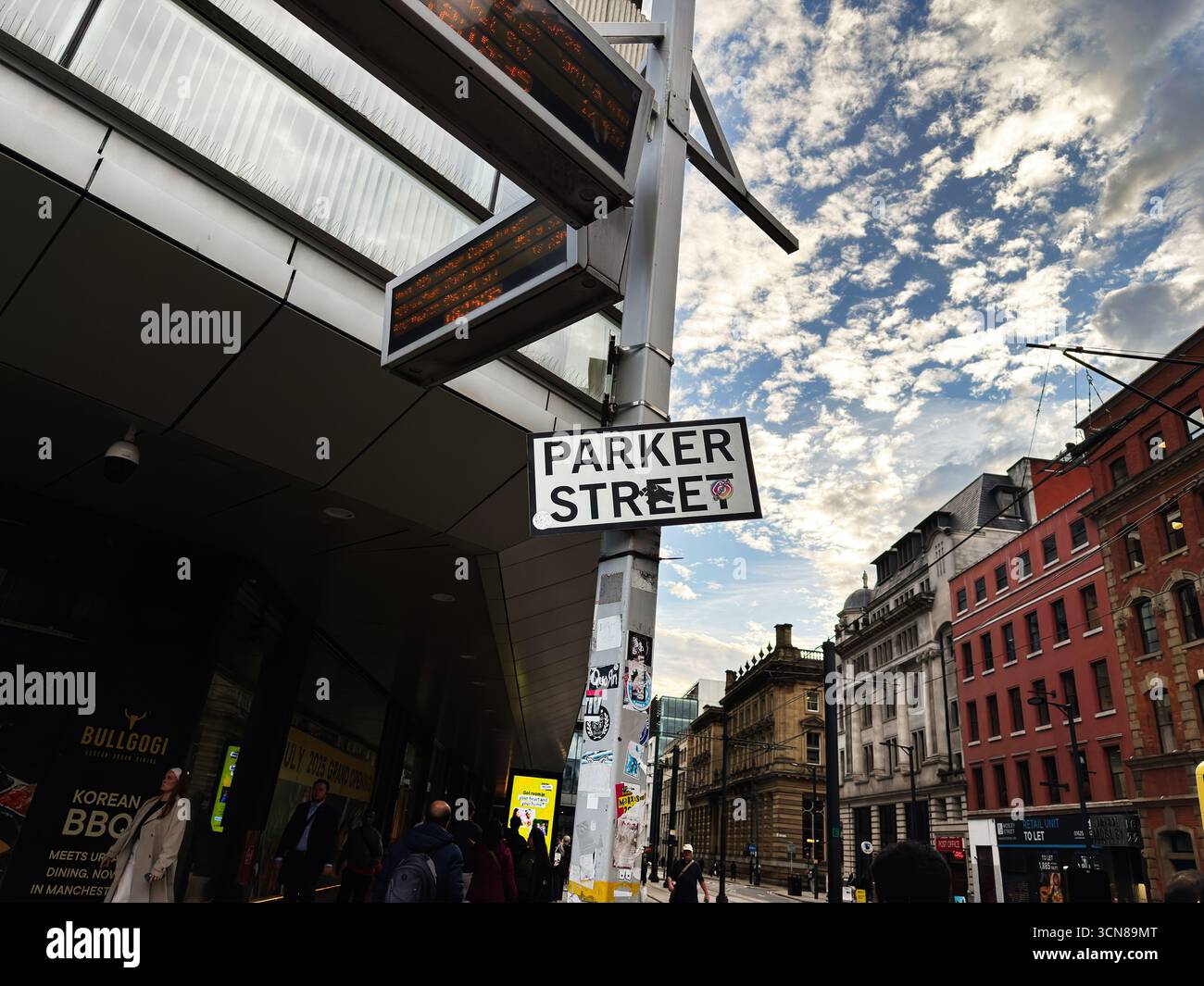 Manchester, Großbritannien - 17. September 2025: Belebte Straßenszene in Manchester mit Parker Street-Schild, Glas- und Backsteinhäusern, Fußgängern und Geschäften. Stockfoto