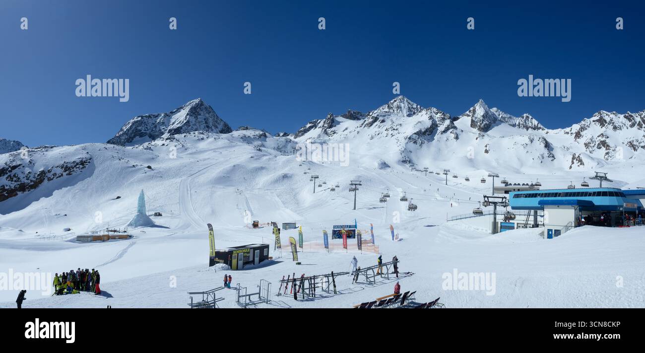 Stubai, Österreich – 8. April 2025: Stubaier Gletscher mit Skipisten, Sesselliften, Skischule, Skifahrern und Snowboardern. Skiständer mit Skiern, Skiliftstatio Stockfoto