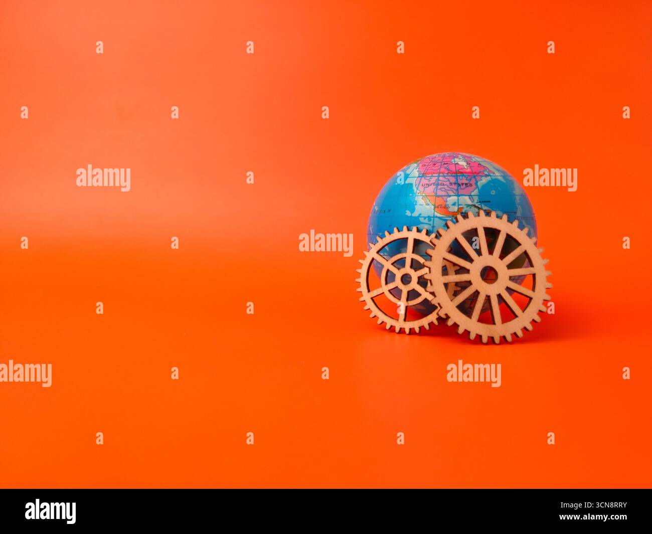 Der Globus neben zwei hölzernen Zahnrädern, die Konzepte in Bezug auf globale Mechanismen, Konnektivität oder die Vernetzung von Systemen vorschlagen. Stockfoto