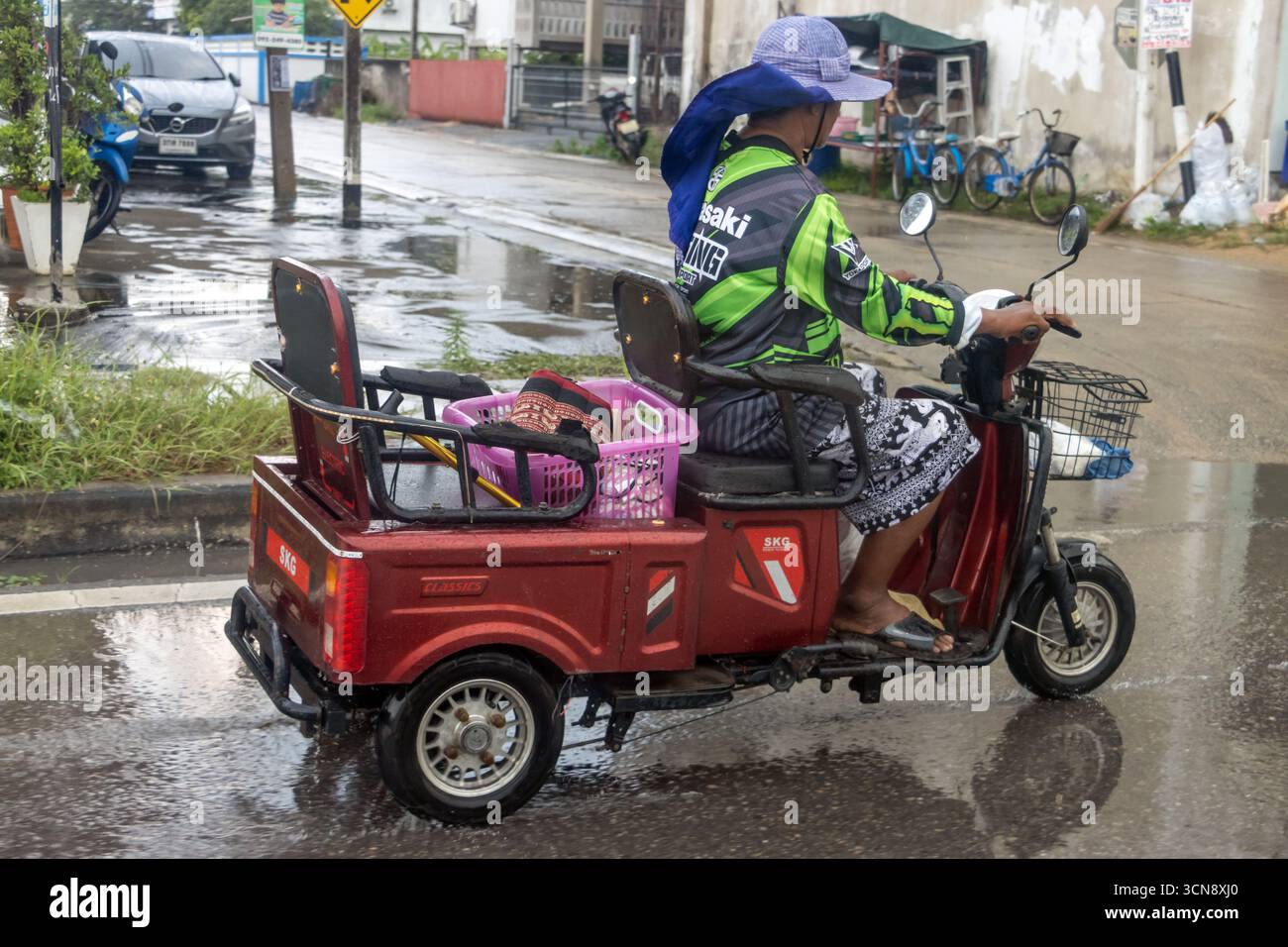 BANGKOK, THAILAND, 06. Oktober 2024, Ein Mann fährt ein beladenes Dreirad auf der Straße im Regen. Stockfoto