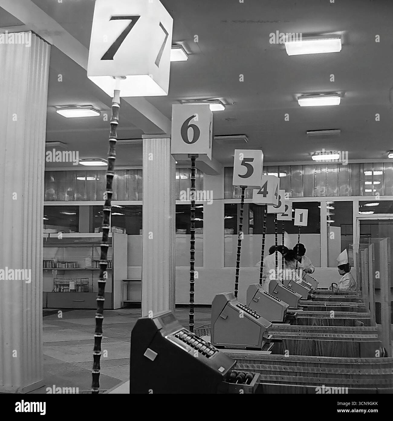 Ein historisches Foto aus dem Jahr 1983, das das Innere des Kaufhauses „Universal“ in Sloviansk, ukrainische SSR, zeigt. Die lange Reihe von Registrierkassen mit nummerierten Schildern im Stil der 1980er Jahre und weiblichen Kassiererinnen in Uniform spiegeln die Atmosphäre und das Design des sowjetischen Handels während der späten UdSSR-Ära wider. Das Bild ist ein authentisches Dokument, das das tägliche Leben und die Routinen der Zeit vermittelt Stockfoto