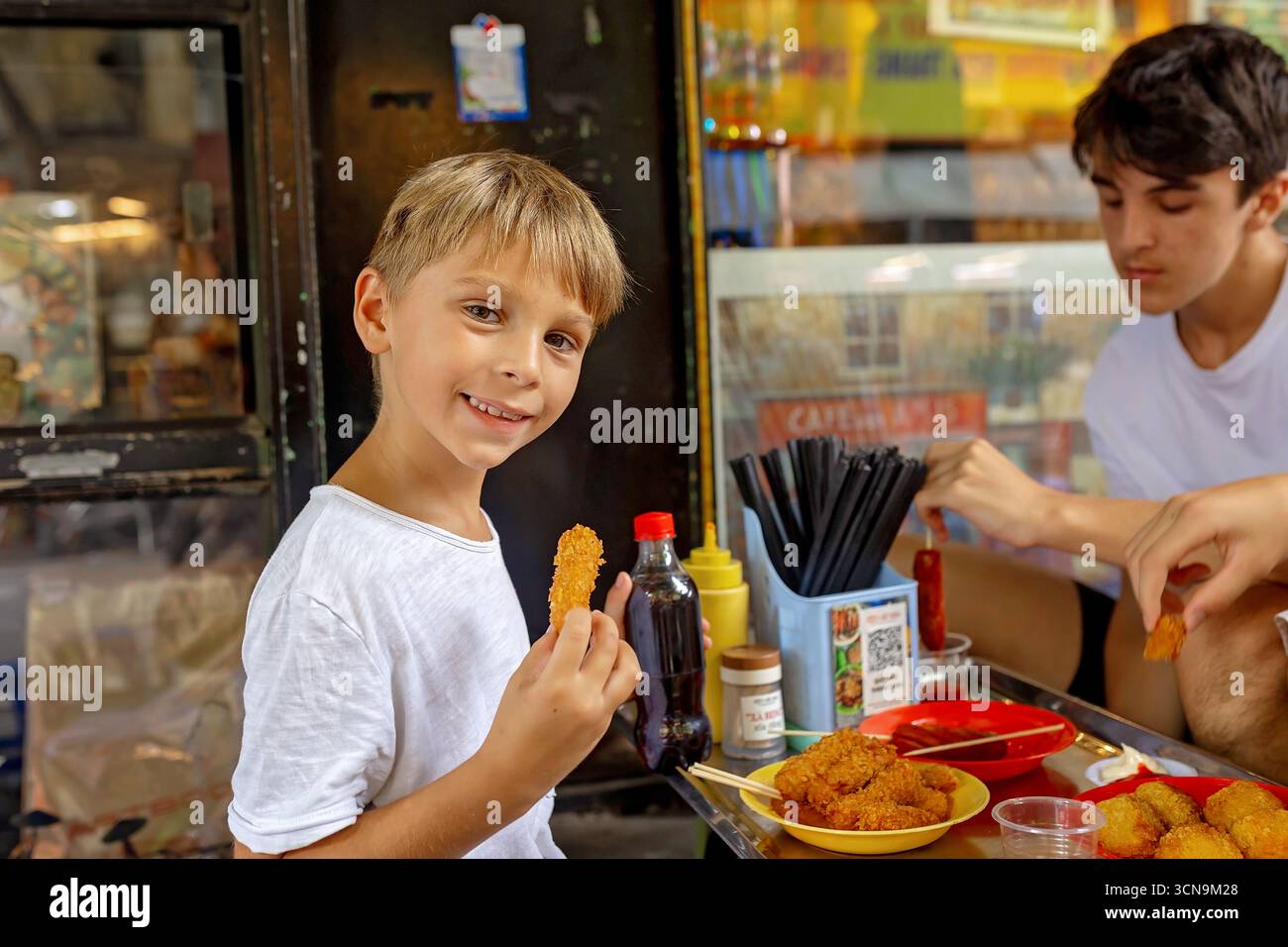 Kinder probieren Street Food in Hanoi, essen traditionelle vietnamesische Küche auf der Straße, kleine Tische und Stühle Stockfoto