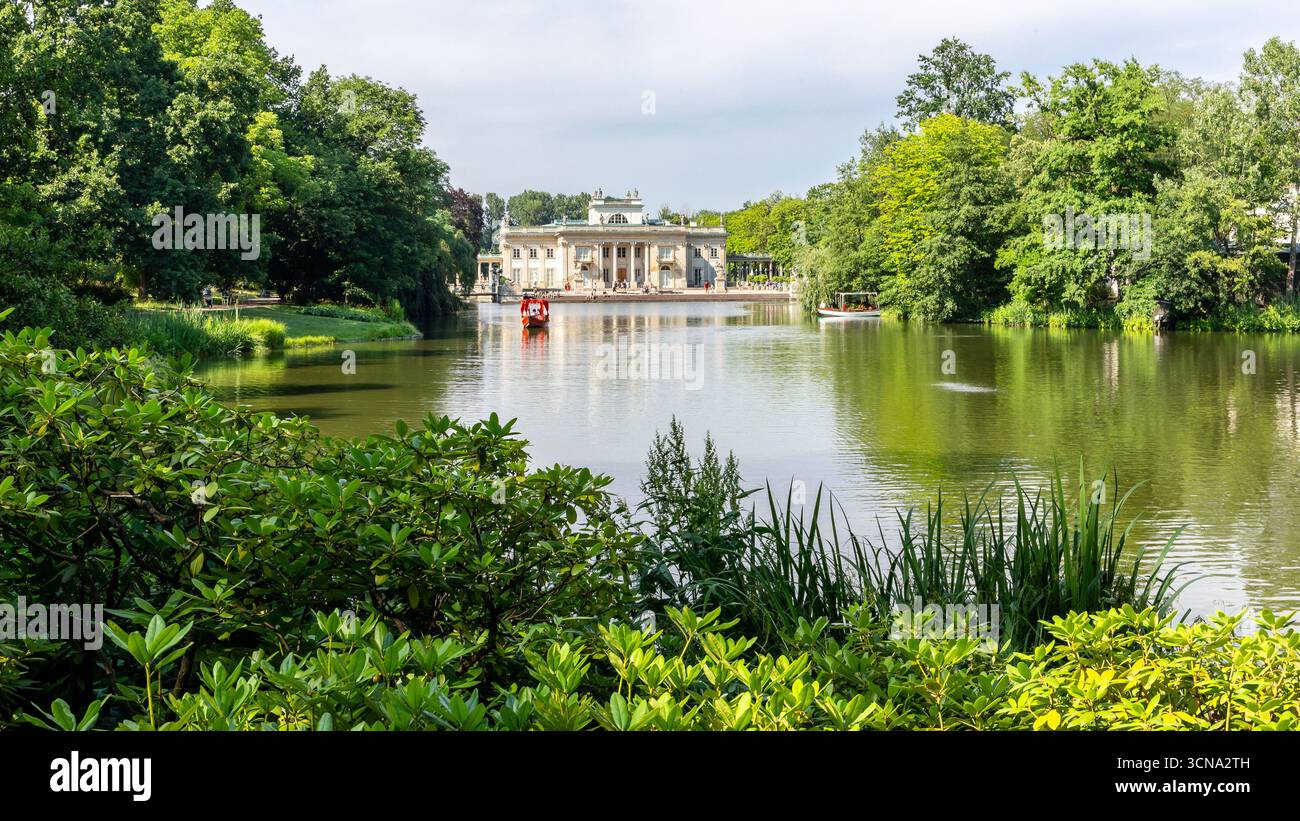 Warschau, Polen, 13.07.21. Der Palast auf der Insel (Polnisch: Palac Na Wyspie) in Warschaus Königspark, Landschaft mit üppiger Vegetation und roter Gondel Stockfoto