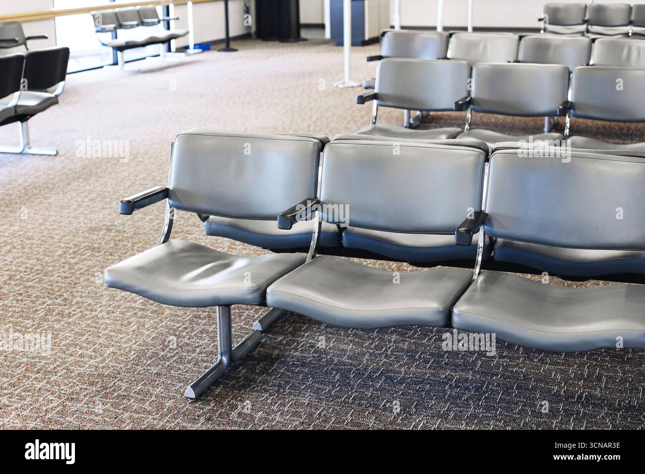 Leerer Flughafensitzbereich mit modernen Metallstühlen. Innere Wartezone des Reisetools. Leere Halle für Passagiere reinigen. Ruhige Atmosphäre wartet auf Sie. Stockfoto
